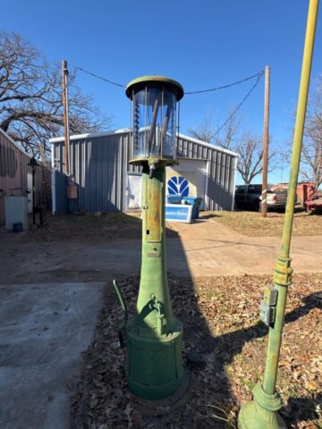 Vintage green hand-crank gas pump with glass cylinder, antique service station collectible