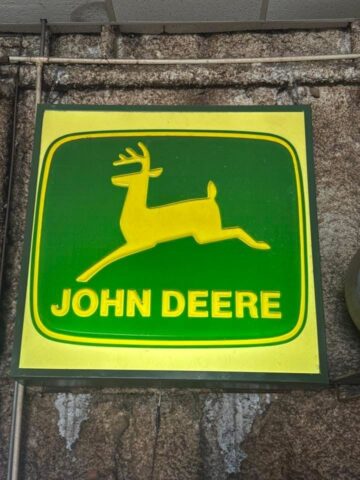 Vintage John Deere illuminated sign with leaping deer logo, classic farm equipment advertising collectible