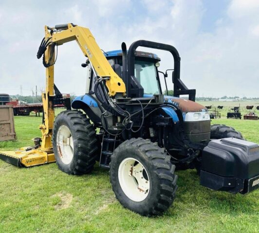 New Holland TS6.110 tractor equipped with a boom mower for sale in upcoming public auction offered by Kiefer Auctioneers in Texas